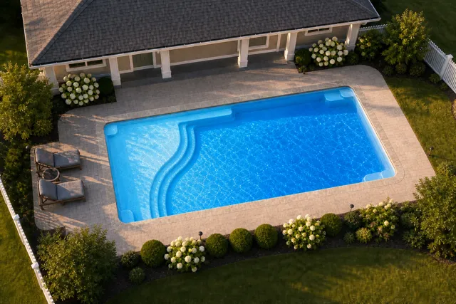 Daytime render of the Aspen 1635 fiberglass pool with stone coping and a California interior, seen from above at an angle.